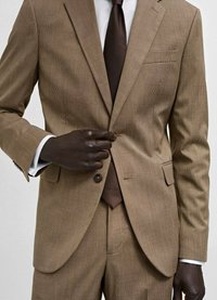 Abito a quadri marrone con revers a punta, chiusura con un solo bottone e cravatta marrone coordinata. Tessuto testurizzato con dettagli di sartoria affilati.