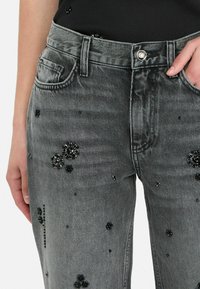 Grijze denim jeans met gemêleerde met bloemen bedekte embellishments, traditionele vijf-pocket ontwerp en een aansluitende taille met een zilveren knop.