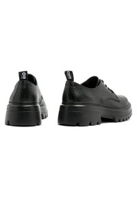 Chaussures en cuir noir avec une finition texturée, design à lacets, semelle extérieure en caoutchouc épaisse et une languette à l'arrière. Bout arrondi avec des coutures subtiles.