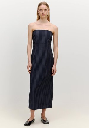 Trägerloses, dunkelblau gestreiftes Kleid mit einem figurbetonten Oberteil und geradem, bodenlangem Rock; Modell trägt schwarze flache Schuhe.