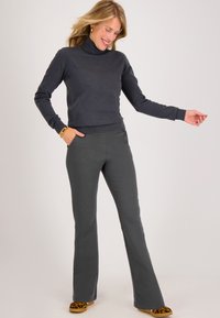 Donkergrijs turtleneck sweater met lange mouwen, gecombineerd met strakke donkergrijze broek. Heeft een gladde textuur en twee voorzakken.