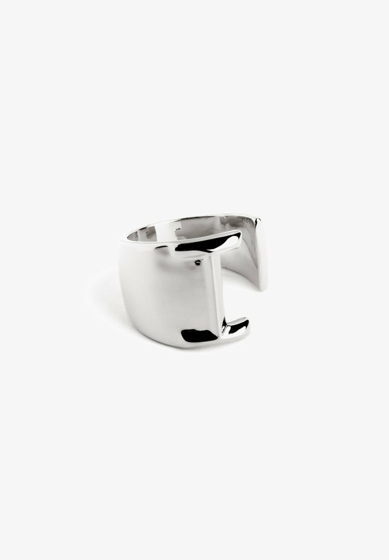 Anello in metallo tono argento, banda larga con finitura lucida e liscia. Presenta un design a ritaglio unico su un lato, creando una forma geometrica moderna.