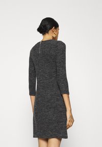Vestito grigio a maglia con maniche a tre quarti, silhouette aderente e dettaglio con cerniera sul retro ben visibile. Tessuto morbido con un motivo sottile.