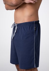 Pantaloni corti blu navy in cotone, con una vita elastica e un laccio grigio, e strisce laterali bianche.