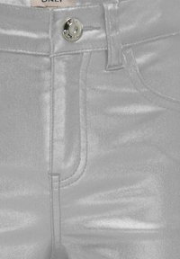 Srebrni metalni skinny jeans z gladko teksturo, ki vključujejo sprednje zapiranje na gumb in dizajn s petimi žepi. Rahla sijajnost po celotni površini.