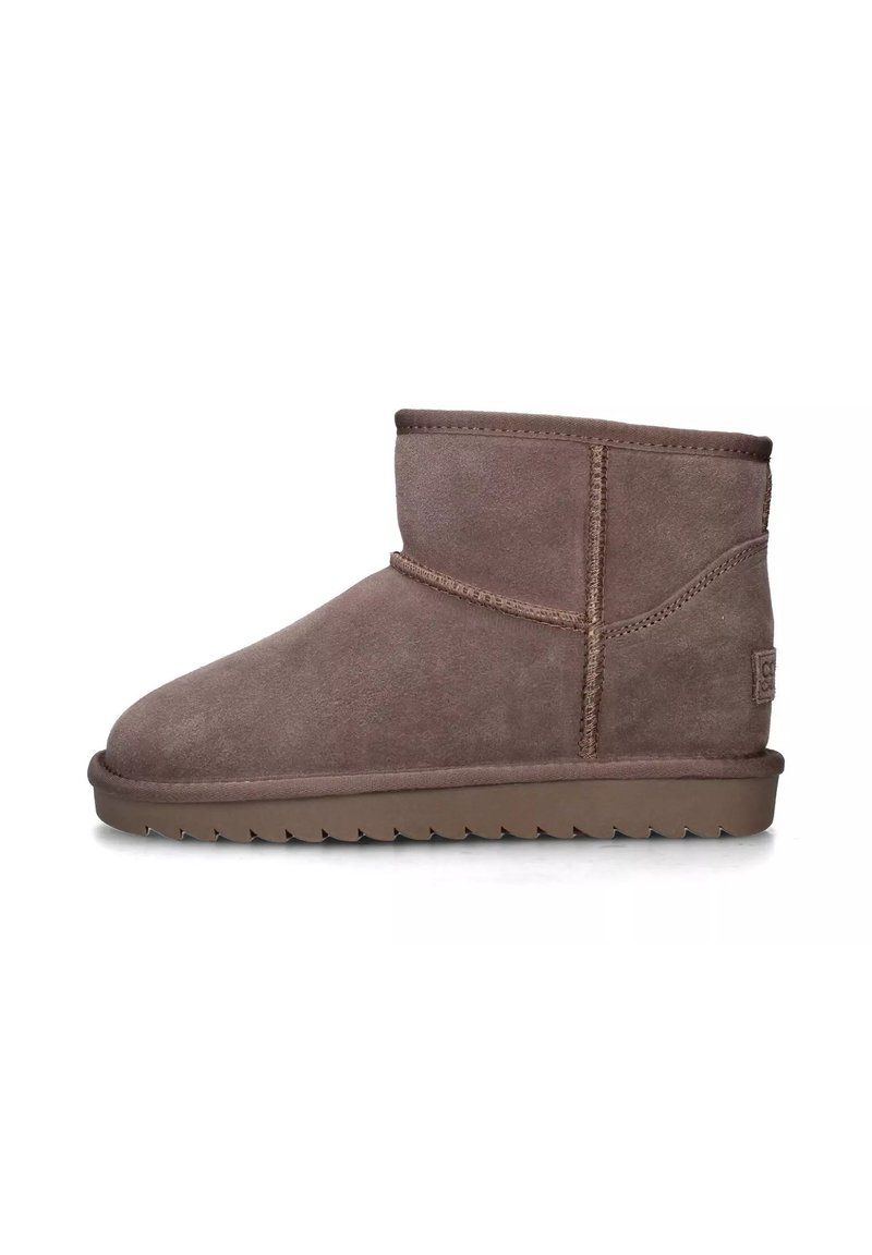 Stivali alla caviglia in suede marrone con una texture morbida, punta arrotondata e cuciture tonali. Suola bassa in gomma marrone con un motivo a zigzag.