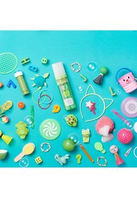 Revlon Equave Kids sprayfles in het groen, omringd door verschillende kleurrijke plastic speelgoedjes, een roze spons, bellen en speelse accessoires op een blauwe achtergrond.