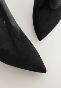 Czarne zamszowe buty na szpilkach z ostro zakończonymi noskami mają siateczkowe akcenty po bokach, gładką teksturę oraz elegancki design, nadający nowoczesny wygląd.
