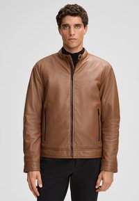 Bruine leren jas met een staande kraag, rits aan de voorkant en twee zijritszakken. Glad textuur met minimale stikdetails.