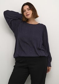 Blusa azul marino con rayas metálicas horizontales, corte holgado, cuello redondo y mangas largas con puños fruncidos; tejido suave y texturizado.