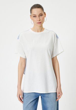 Hvid bomulds T-shirt med korte ærmer, der har blå stribede detaljer på skuldrene. Afslappet pasform og enkelt crew neck design.