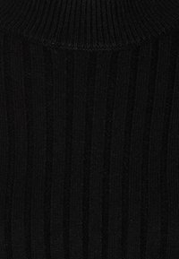 Schwarzer Strickpullover mit gerippter Textur, hohem Kragen und taillierter Silhouette. Das Material wirkt weich und dehnbar.