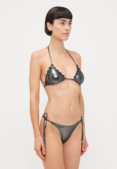 Metalno siva bikini s trokutastimi čašicami in cvetličnim čipkastim obrobom. Nastavljive vezalke na bokih. Gladka tekstura, zasnova z minimalnim pokrivanjem.