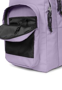 Lila ryggsäck med en texturerad svart meshficka, zippered frontfack och svarta dragkedjor. Tillverkad av hållbart tyg.