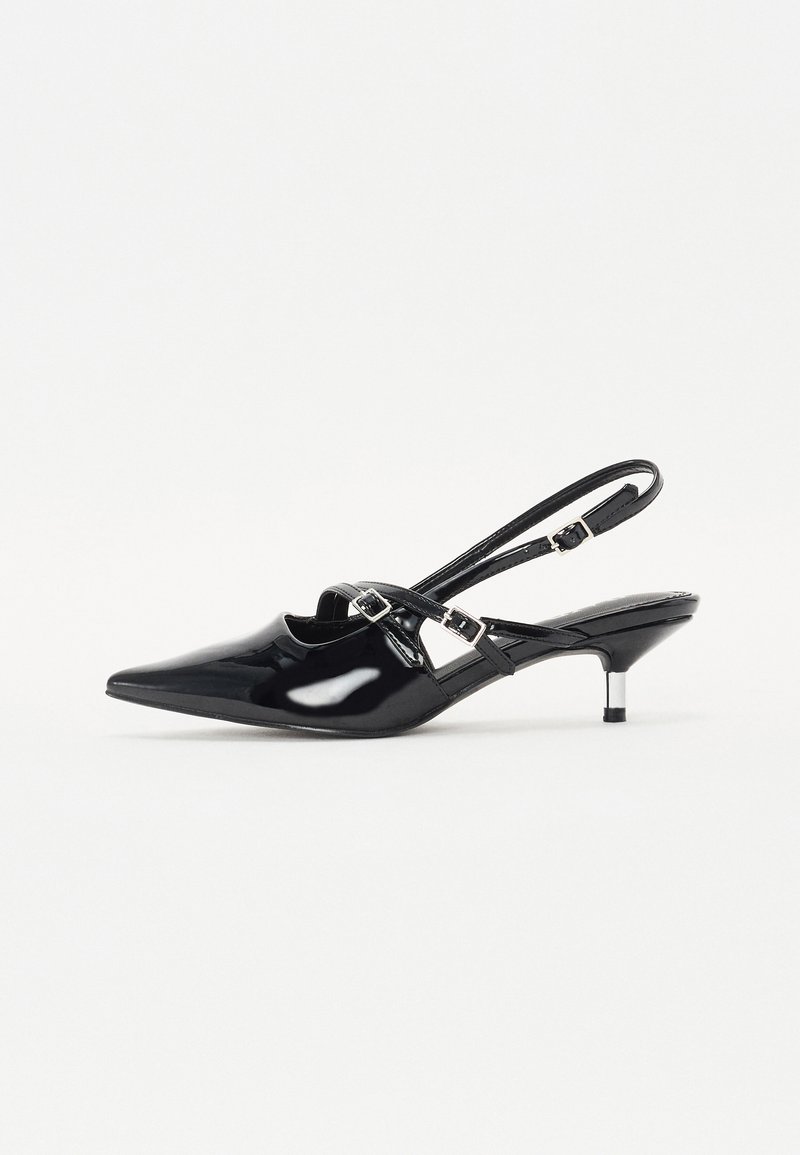 Crne lakirane slingback cipele s nazupcima, uskim potpeticama i podesivim kopčanjem preko sredine stopala. Glatka tekstura.