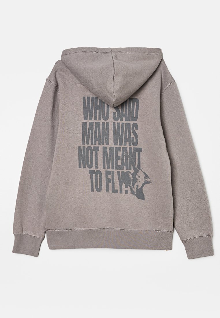 Hellgrauer Hoodie mit großem, dunkelgrauen Schriftzug auf dem Rücken "WER HAT GESAGT, DASS DER MENSCH NICHT FLIEGEN SOLLTE?" und einer kleinen Grafik einer Person mit Flügeln.