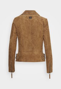 Bruine suède jacket met een aansluitend ontwerp, gegroefde kraag en ritssluitingen bij de mouwen. Beschikt over dubbele gespaccenten in de taille voor aanpassing.
