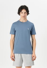 T-shirt en coton bleu à manches courtes et col rond, avec un petit logo brodé sur la poitrine gauche. Assorti à un short rayé.
