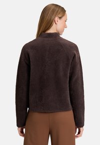 Giacca in pile marrone, morbida e lanosa, con colletto alto e maniche lunghe; presenta una silhouette rilassata e una consistenza soffice. Mostrata dal retro.