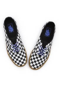 Black and white checkered canvas sneakers with blue laces, rubber sole, and logo on tongue. Flat, low-profile design.
