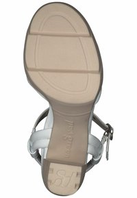 Sandalo bianco in pelle con suola in gomma beige modellata. Presenta cinturini incrociati, una fibbia alla caviglia e dettagli testurizzati sulla soletta.