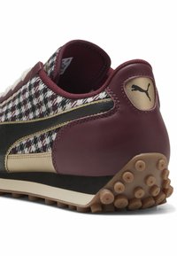 Sneaker bordeaux e nera con un motivo a spina di pesce testurizzato, accenti in pelle, dettagli dorati e suola in gomma con battistrada circolare.