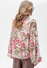 Langärmlige Bluse aus leichtem Stoff mit floralem Muster in Rosa- und Grüntönen; leicht ausgestellt Ärmel und lockere Passform.