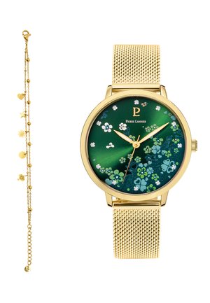 Auksinis tinklelio dirželis, laikrodis su žaliu gėlių ciferblatu ir auksinėmis rodyklėmis, kartu su subtilia auksine apyranke su įvairių formų pakabučiais.