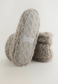 Fnug grå sutsko med en tekstureret plys-overdel, sammenfoldeligt design og let gummisål med et fiskebensmønster. Størrelsesmærke synligt.