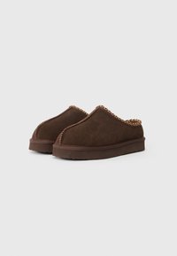 Brune ruskinds slip-on sko med en rund tå, der har en tekstureret søm langs toppen og en tyk, polstret sål.