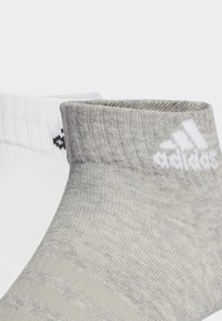 Calcetines tobilleros de mezcla de algodón en blanco y gris claro. Las características incluyen una textura acanalada, logotipos en contraste y un diseño ajustado para mayor comodidad.