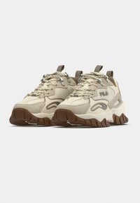 Χοντρά αθλητικά παπούτσια σε εκρού και καφέ, με υφή στην επάνω επιφ άνεια, μεταλλικά φερμουάρ, ανάμεικτα υλικά και χοντρή εξωτερική σόλα από καουτσούκ.