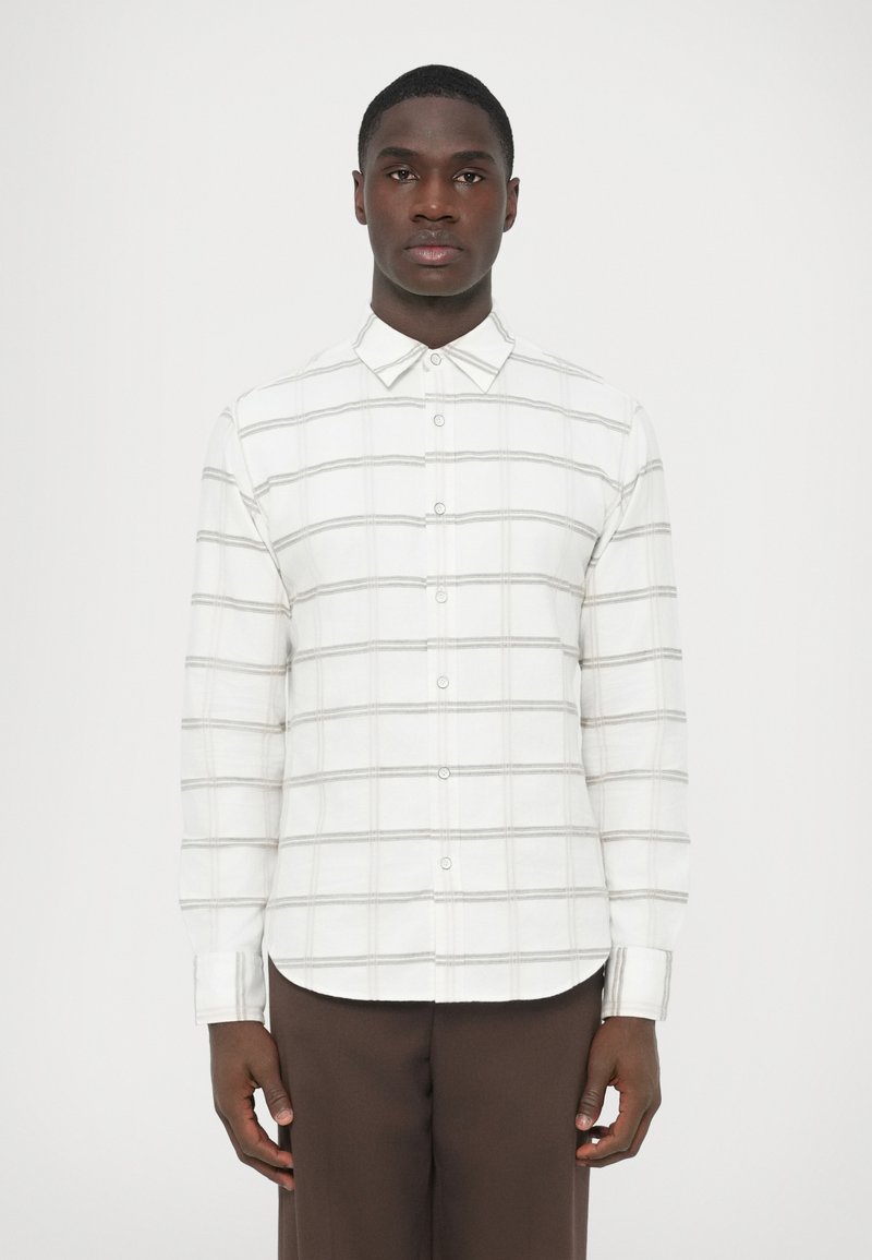 Witte blouse met lange mouwen en knopen, voorzien van een grijs ruitpatroon, met een klassieke kraag en een rechte zoom. Het materiaal lijkt zacht en glad.