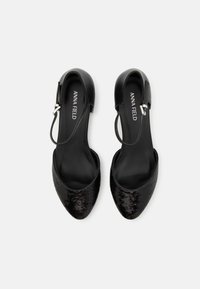 Mustat slingback-kengät, joissa on kärki suunnittelussa. Yläosa on koristeltu paljeteilla; säädettävä hihna hopeaosilla.