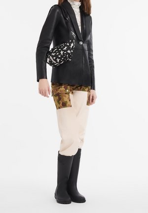 Czarna skórzana marynarka, kamuflażowe spodnie cargo, kremowe spodnie i czarne gumowe buty; czarna torba z białym wzorem gwiazdy.