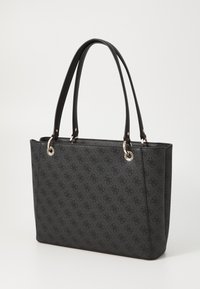 Sac fourre-tout noir en matériau texturé, doté de quincaillerie en argent, de deux poignées et d'un motif en relief sur l'extérieur.