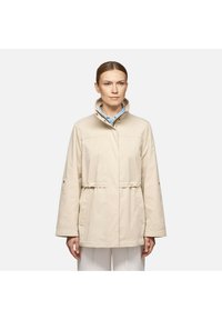 Giacca beige con colletto alto, vita elastica e maniche lunghe. Realizzata in un tessuto morbido con tasche laterali e vestibilità comoda.