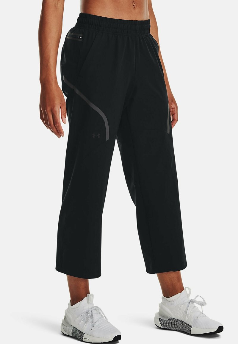Black cropped athletic pants with an elastic waistband, featuring grey accents and zippered pockets. Made of lightweight, flexible material.
