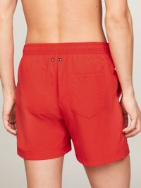 Costumi da bagno rossi con cintura elastica, dotati di tasca posteriore e due bottoni decorativi. Texture liscia e lunghezza sopra il ginocchio.