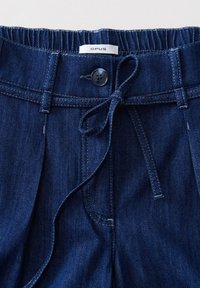 Dunkelblaue Denim-Hosen mit einem Kordelzugbund, Knopfverschluss und vorderen Taschen. Mit kontrastierenden Nähten und einem weichen, strukturierten Stoff.