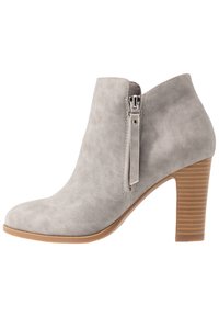 Botín de ante sintético gris con puntera redondeada, detalle de cremallera lateral y tacón apilado con estrías verticales. Textura suave y diseño elegante.