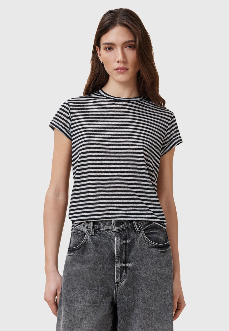 T-shirt à manches courtes rayé noir et blanc avec un col rond, associé à un jean en denim noir délavé taille haute.