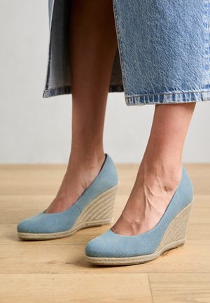 Lichtblauwe sleehakschoenen met een bovenwerk van gladde stof en een zool met een geweven jute-achtige structuur. Rond neusontwerp met een laag uitgesneden wreef.