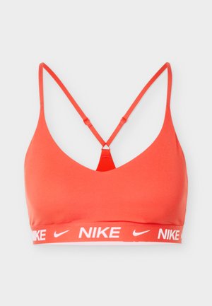 Koraalroze sportbeha met dunne racerbackbandjes en een elastische band met witte Nike-logo's en swooshes.