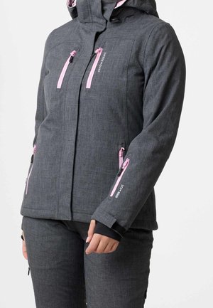 Vrouw draagt donkergrijze capuchonjas en bijpassende broek met roze ritssluitingsdetails op borst, mouwen en zakken.