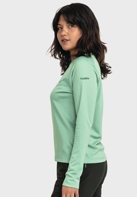 Langärmliges, mintgrünes Sportshirt mit Rundhalsausschnitt und strukturiertem Stoff. Es verfügt über ein Logo auf dem linken Ärmelschnitt und hat einen lässigen Schnitt.