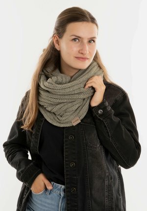 Lichtgroene gebreide infinity sjaal met een textuurpatroon. Gecombineerd met een zwarte denimjack en een zwart topje. Casual gedragen.
