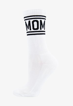 Chaussette blanche de cheville avec le texte "MOM" en noir et deux rayures noires en haut. Texture côtelée et forme ajustée pour le confort.
