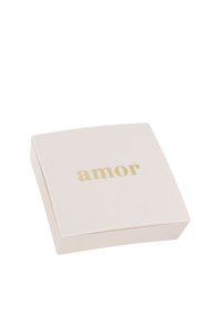 Kvadratisk, ljusrosa låda med en slät yta, med ordet "amor" i guldbokstäver på locket. Enkelt, elegant design.