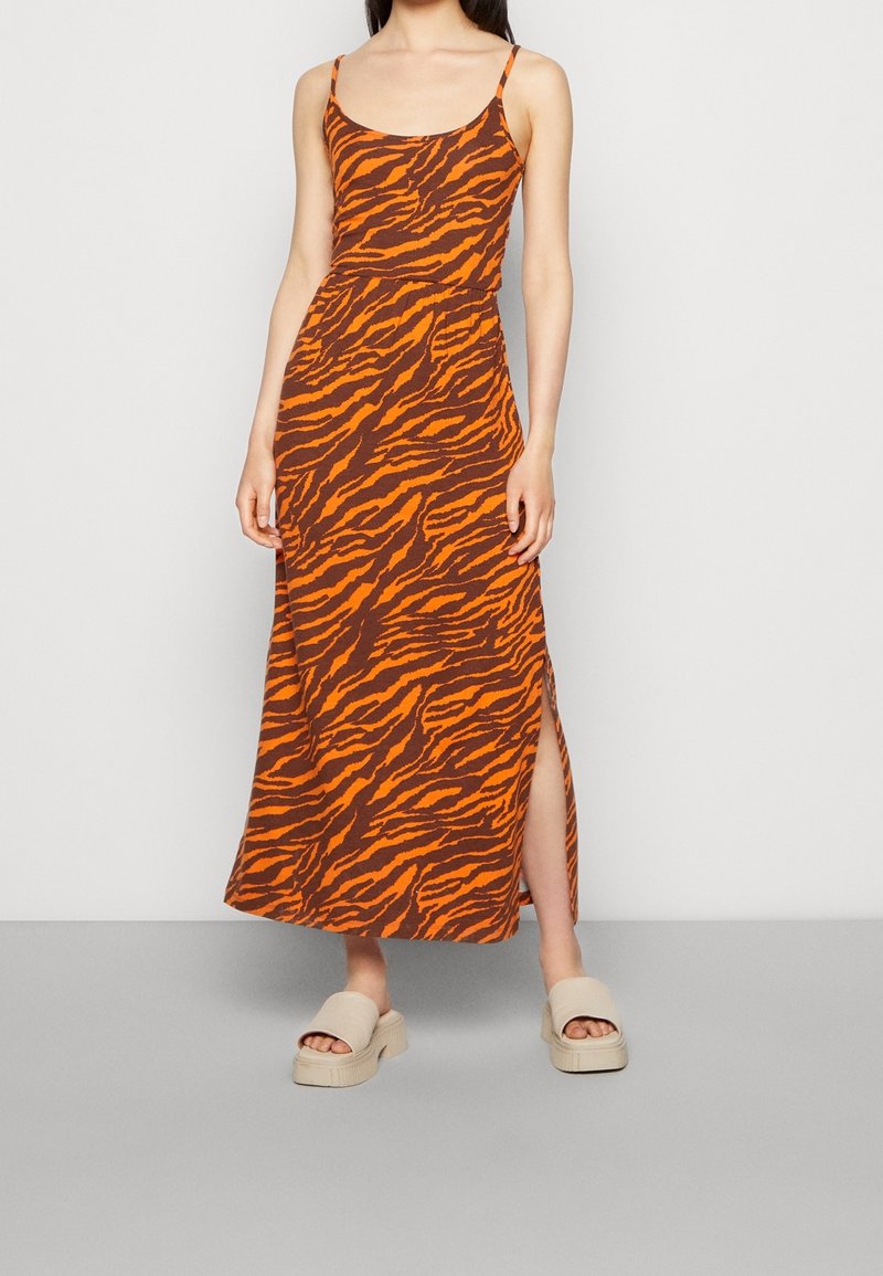 Robe longue à imprimé rayures tigre en marron et orange, avec bretelles fines et fente latérale. Confectionnée dans un tissu doux et léger.